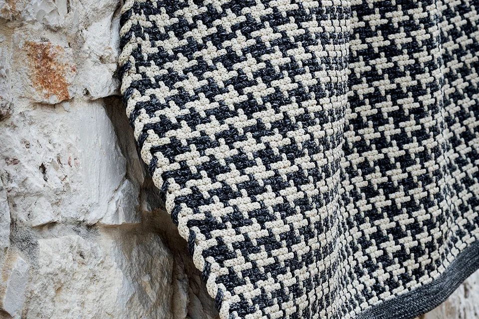 Dettaglio ravvicinato della trama bicolore dei tappeti outdoor Aladdin per forniture contract e arredo professionale