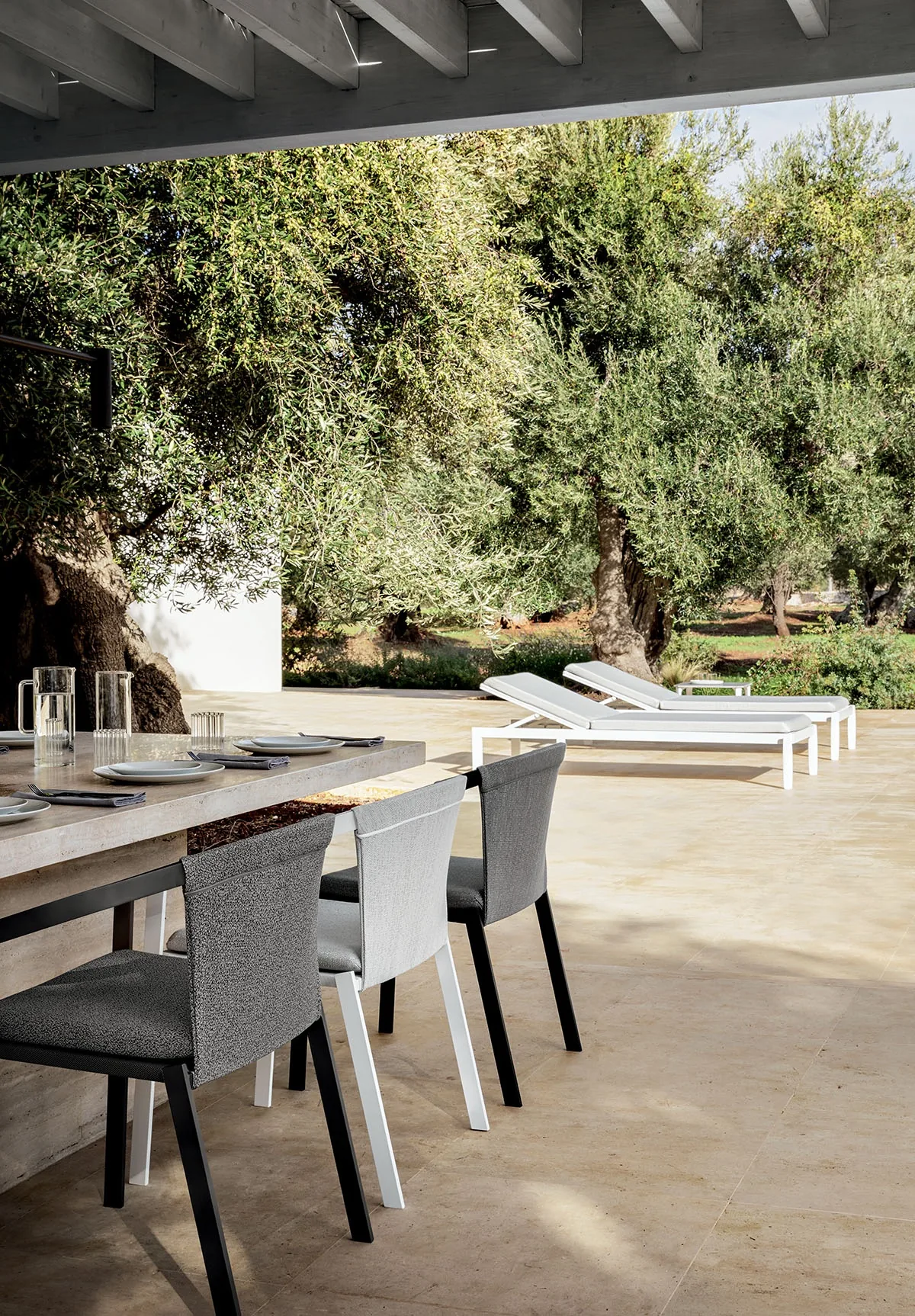 Grande tavolo rettangolare in marmo con otto sedie Push Rope disposte in un patio moderno in Puglia