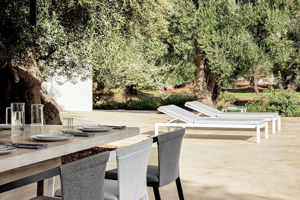 Grande tavolo rettangolare in marmo con otto sedie Push Rope disposte in un patio moderno in Puglia