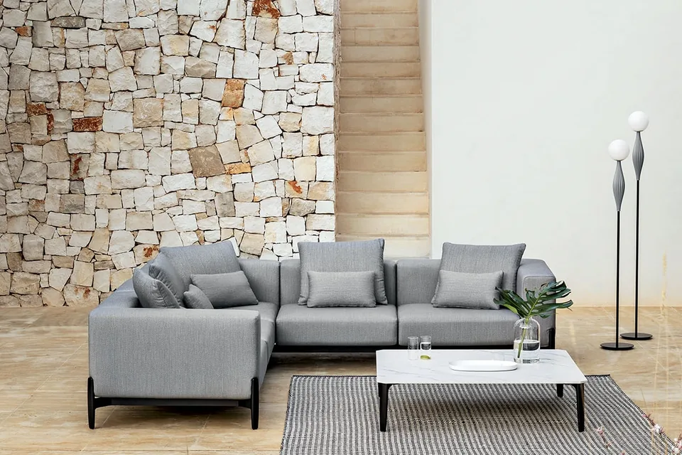 Divano angolare modulare Push grigio di MYYOUR in un'area lounge esterna con muretti in pietra in Puglia