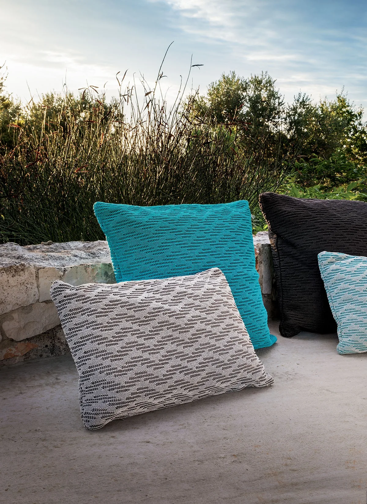 Cuscini decorativi per esterni della linea Wave MYYOUR su un tipico muretto a secco in Puglia