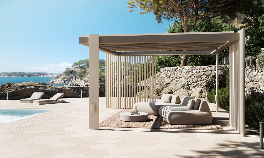 Pergola CODE addossata a una villa sul mare, divano e chaise longue sotto la copertura